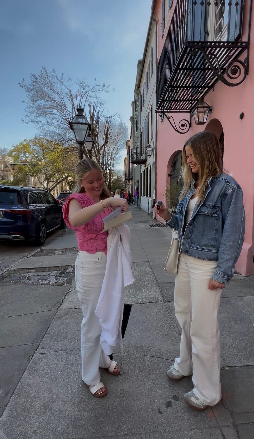 Two friends opening a card on a colorful Charleston street