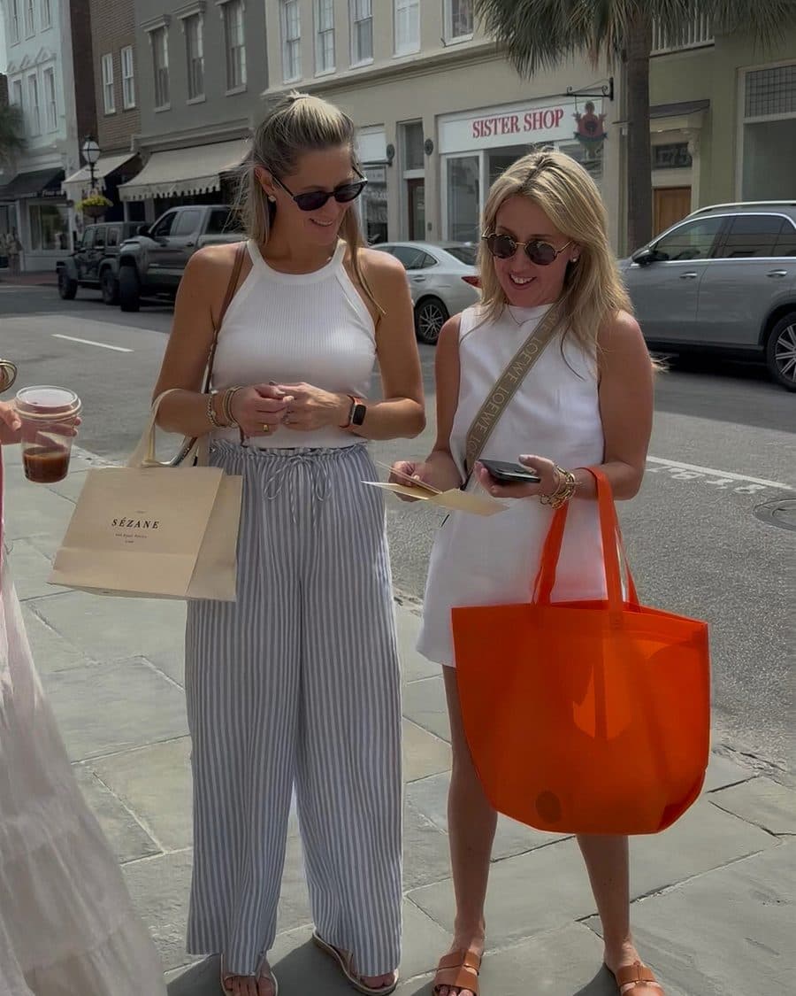 Two women sharing a card on a sunny street